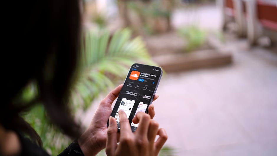 A woman browsing app on her smartphone outside with focus on hands and device.