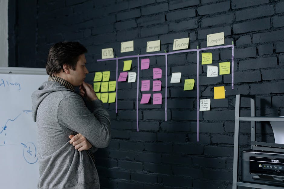 Adult male focusing on task planning using sticky notes on a black wall in a contemporary office setting.